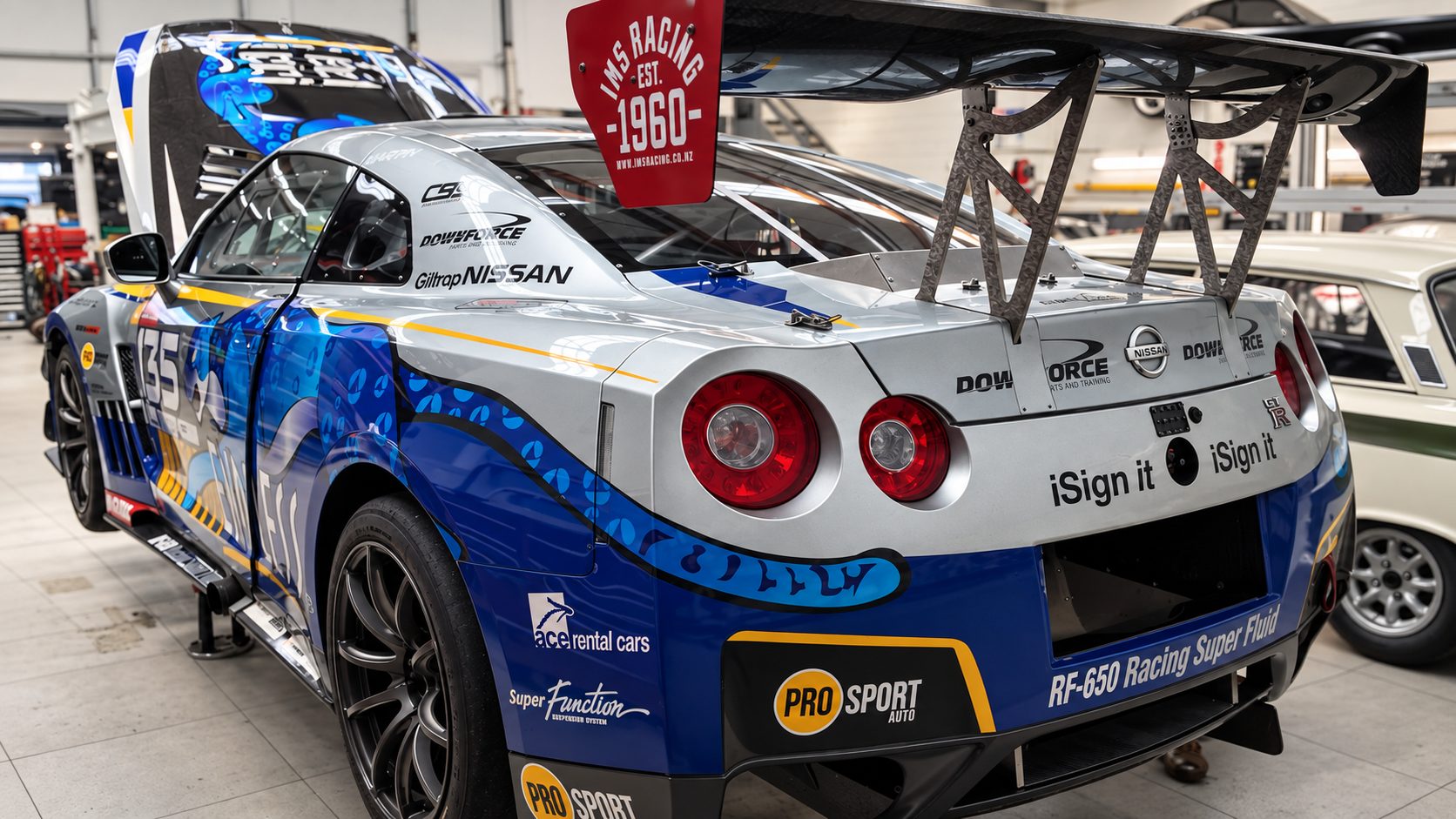 Race car with a carbon fibre rear wing inside a workshop