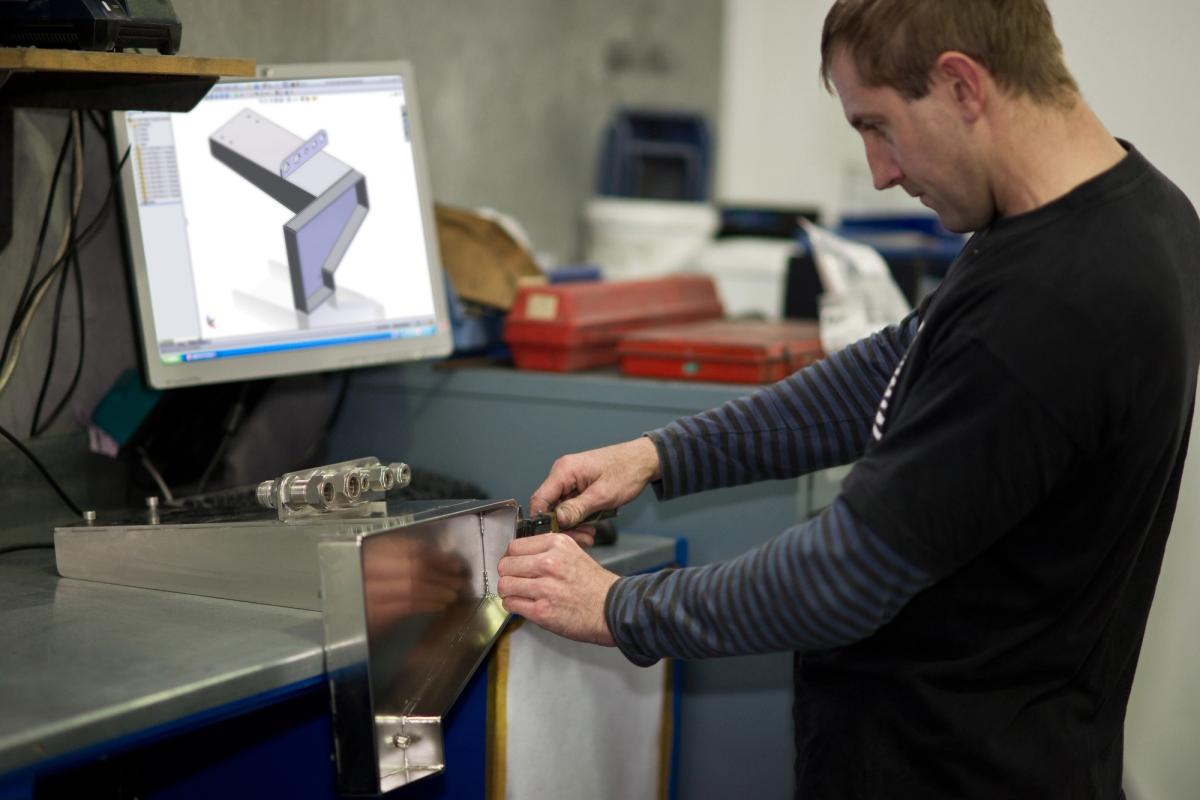 Composite technician working from a 3D CAD model to manufacture a precision metal component