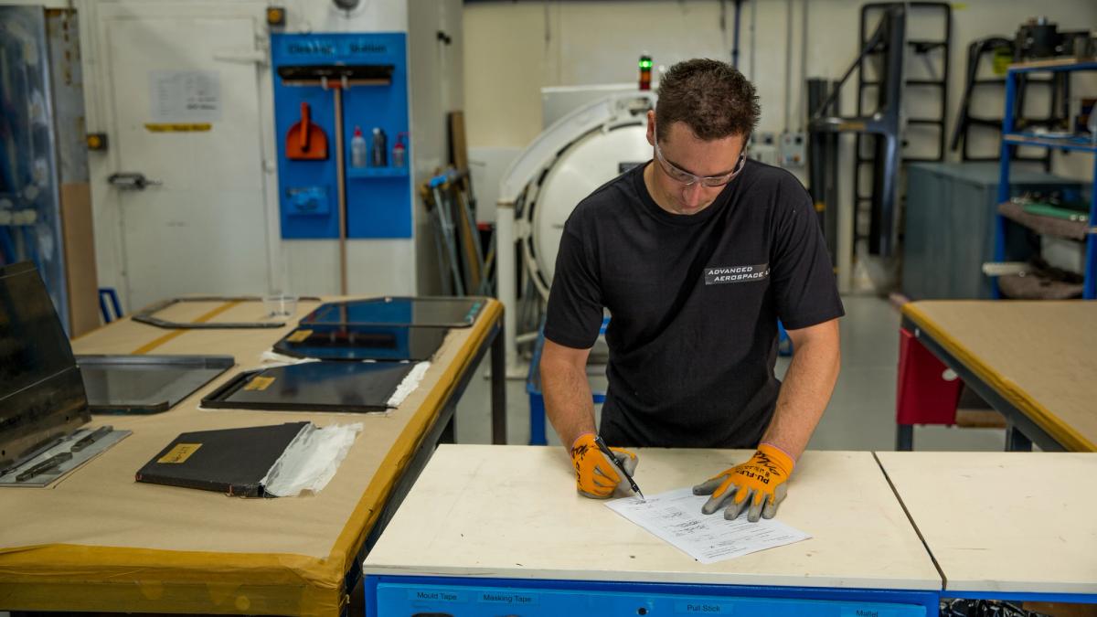 Advanced Aerospace technician signing off documentation beside composite interior panels