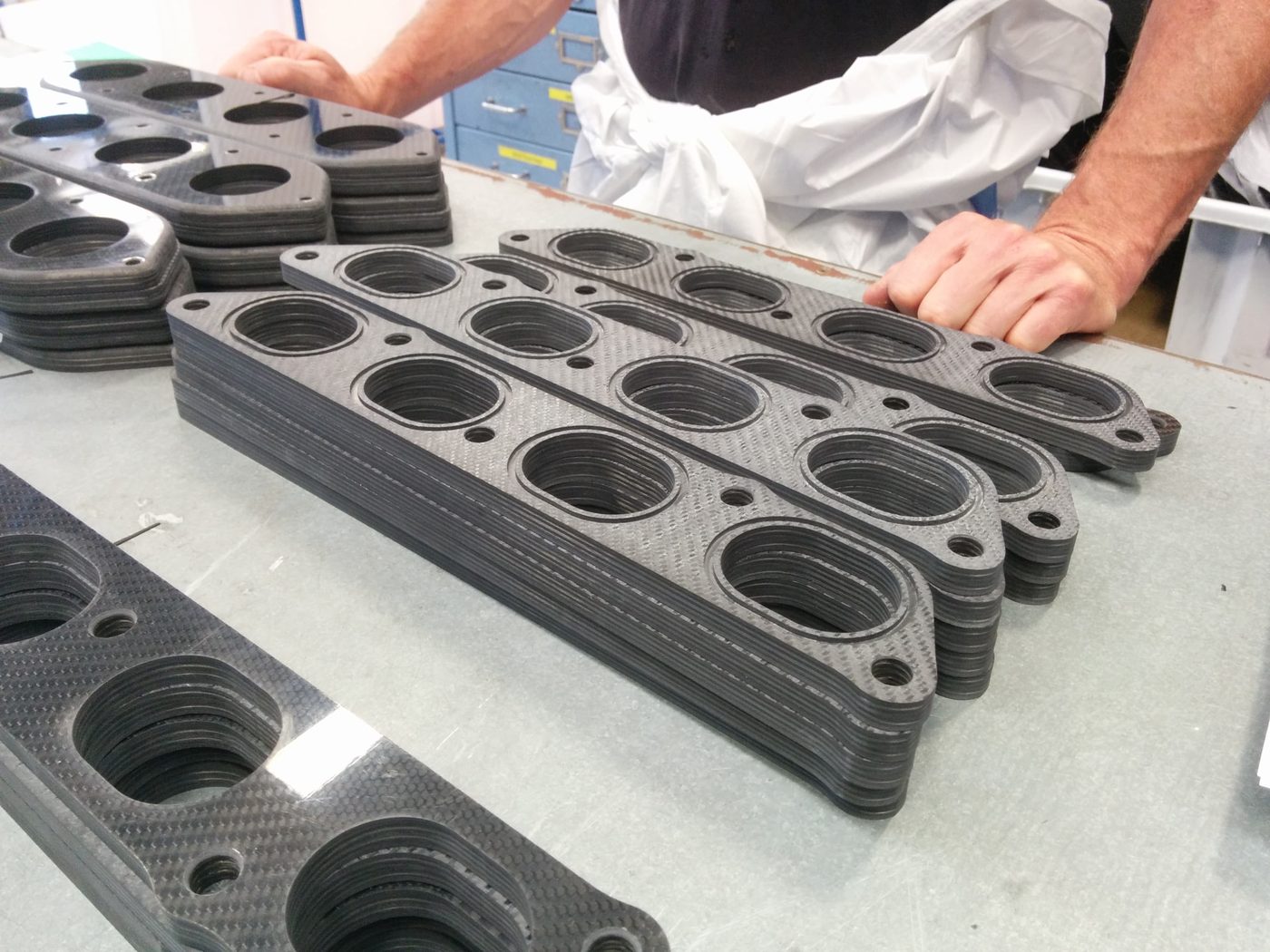 Machined carbon fibre components stacked on a workshop bench