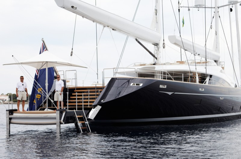C-Quip swim stairs deployed into the water from the swim platform of a dark-hulled sailing superyacht