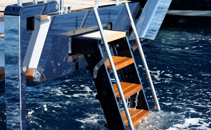 Close view of C-Quip swim stairs showing teak steps, carbon-fibre side structures and stainless steel handrails