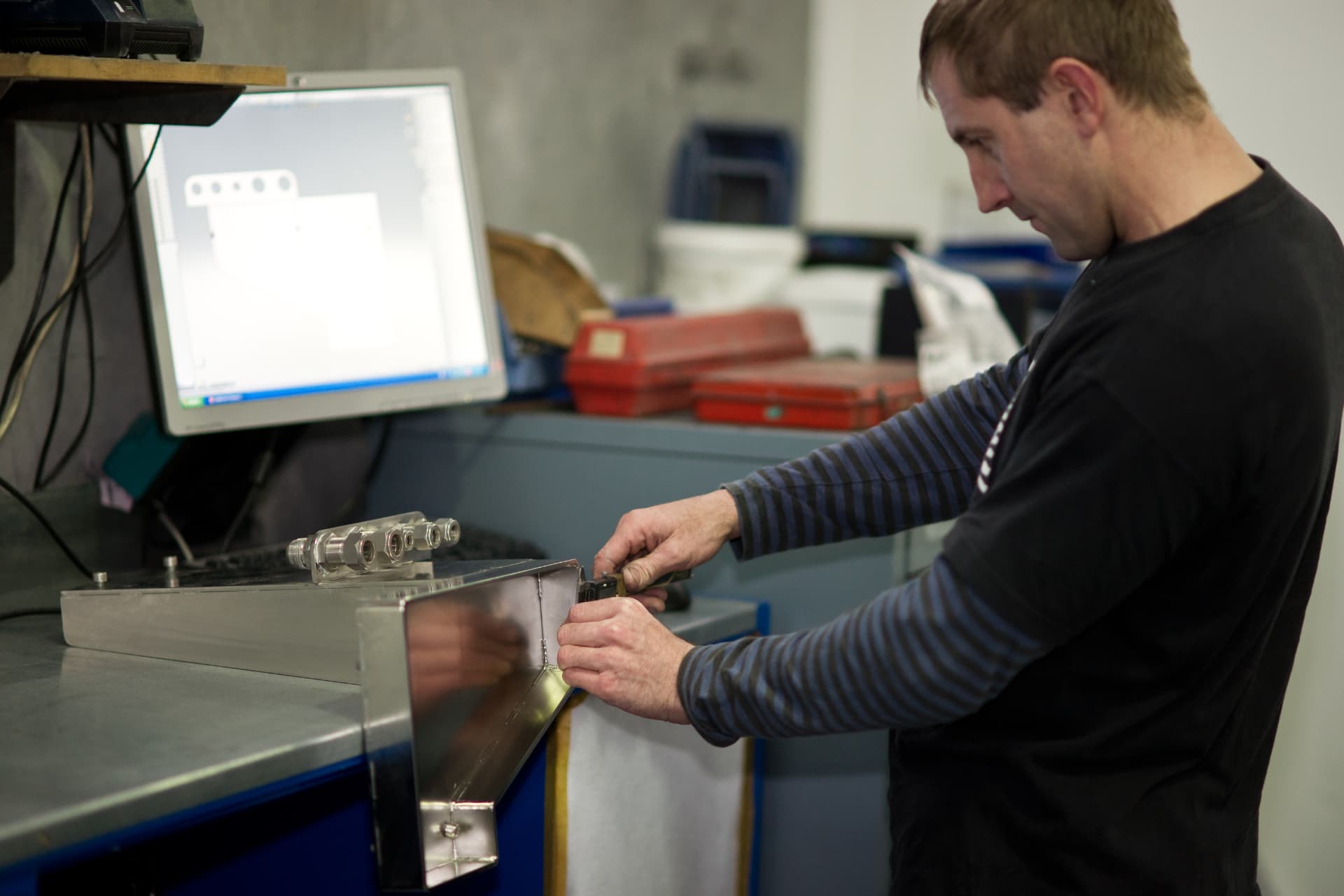 C-Quip technician reviewing precision metalwork against a technical drawing